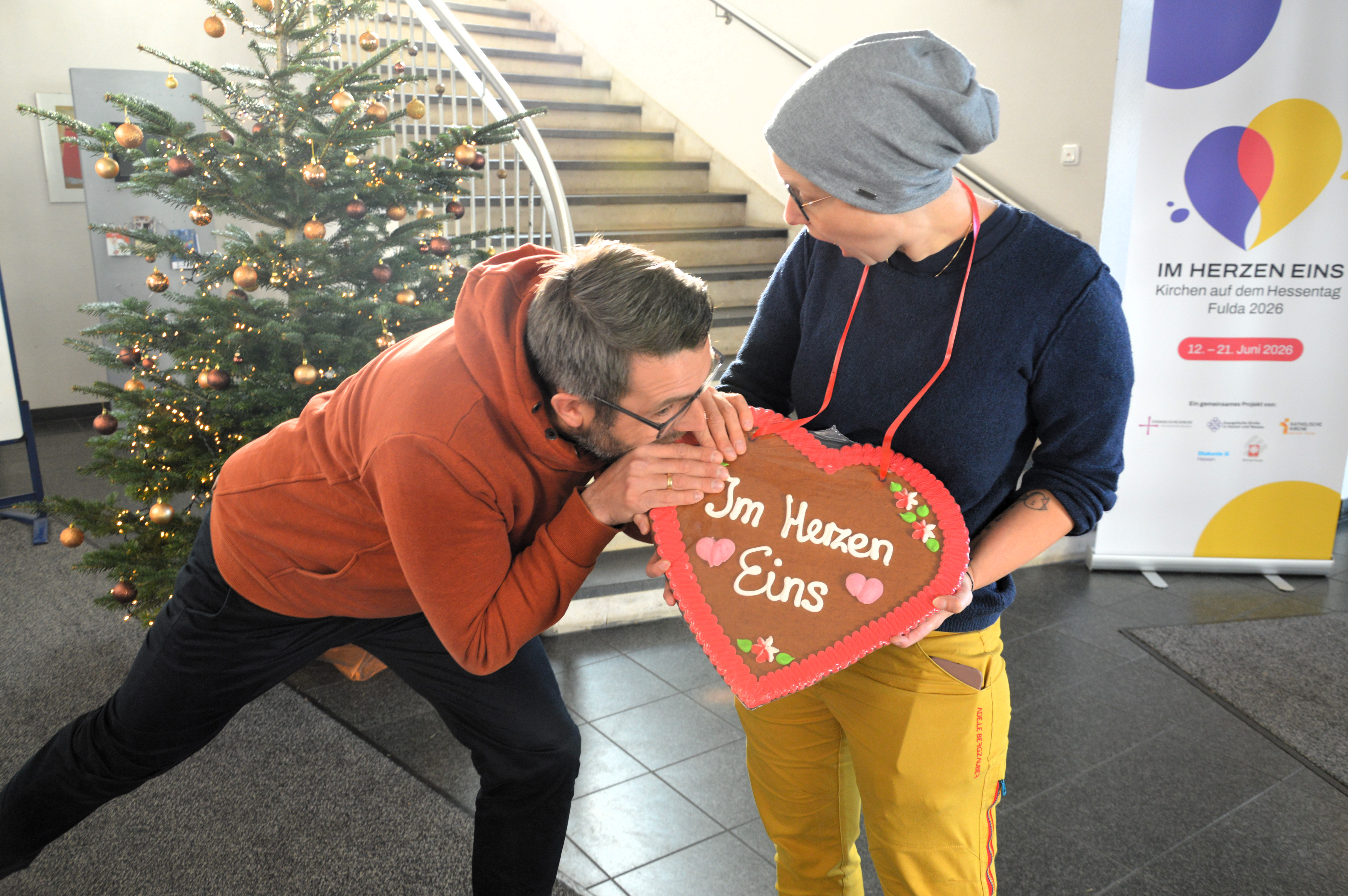 Zwei Mitglieder der Projektgruppe halten ein Lebkuchenherz mit dem Motto "Im Herzen eins".
